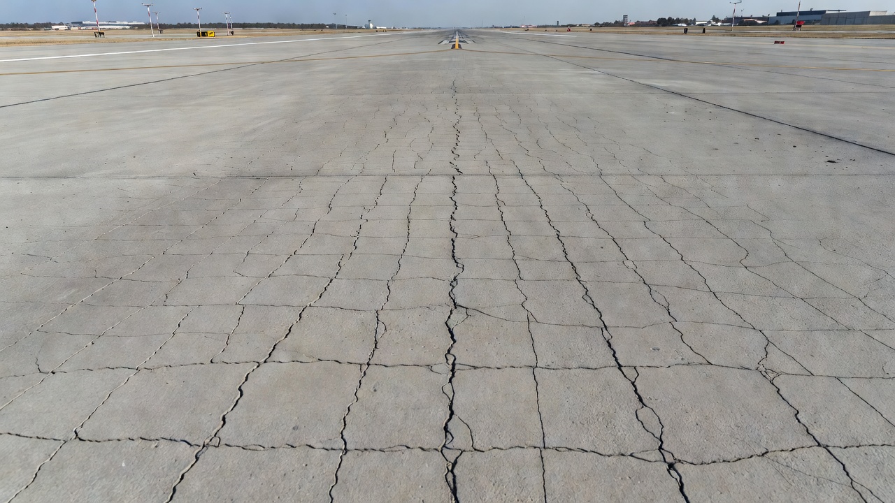 Piste aéroportuaire en béton montrant un motif de fissuration cartographique fine sur la surface de la chaussée