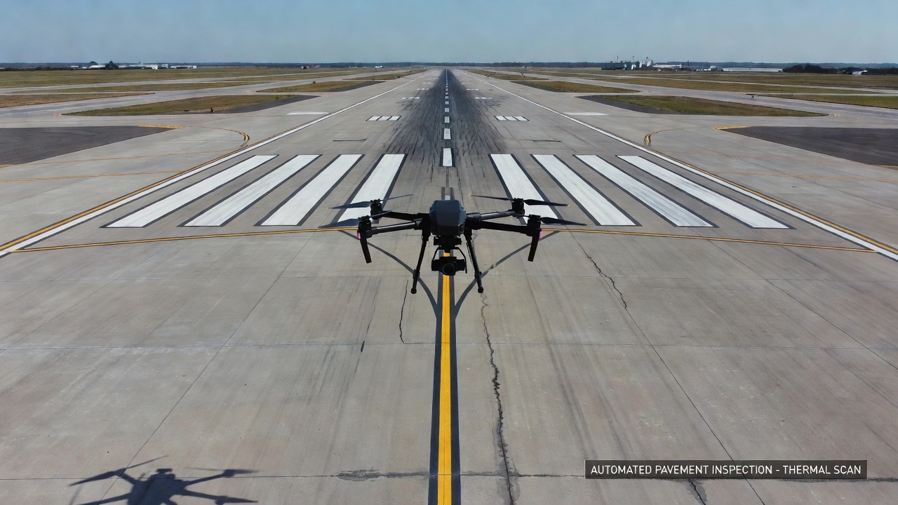 Drone effectuant une inspection automatisée de chaussée sur une piste d'aéroport en béton avec charge utile d'imagerie thermique