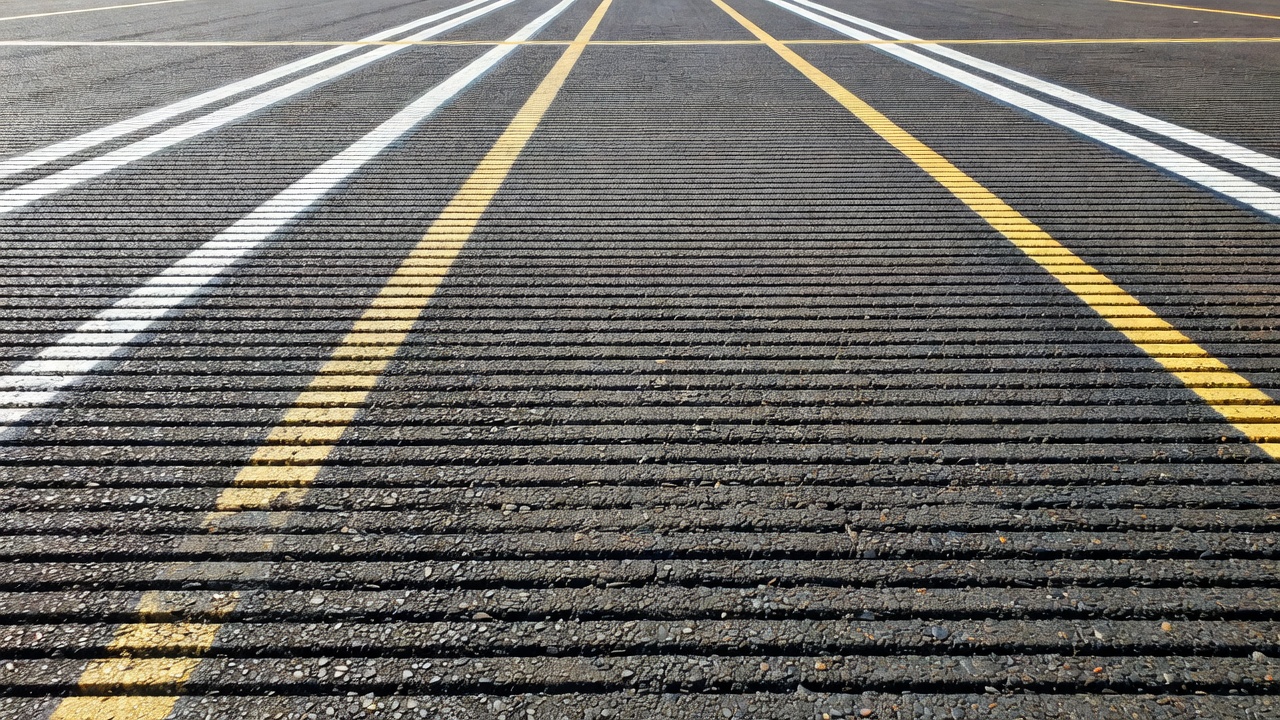 Rainurage transversal de piste — canaux de 6 mm de large, 6 mm de profondeur espacés de 32 mm — fournissant des voies de drainage d'eau essentielles pour prévenir l'aquaplanage et maintenir la résistance au dérapage sur pistes mouillées