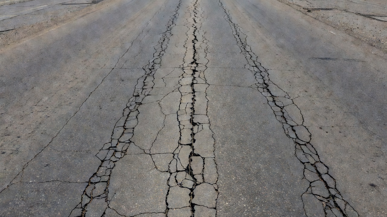 Surface de chaussée en béton avec une fissure longitudinale visible courant parallèlement au bord de la chaussée