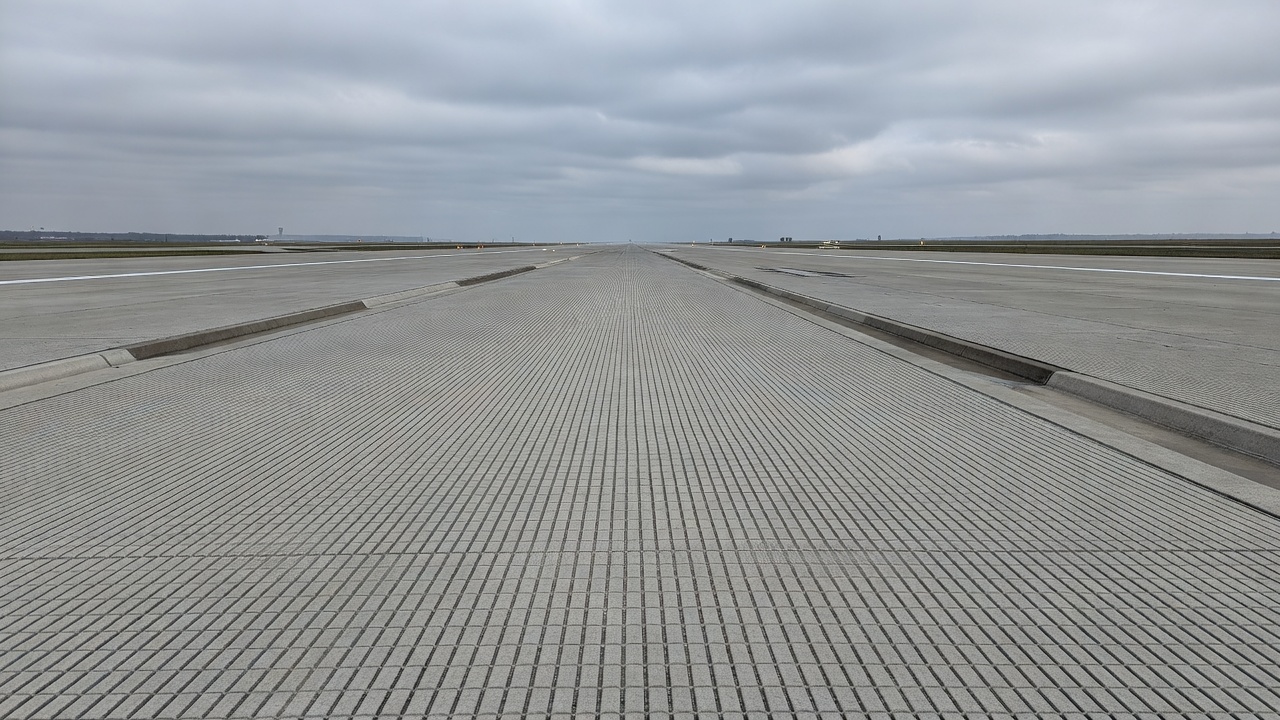 Surface de piste d'aéroport avec un motif de rainurage transversal frais, canaux de drainage parallèles étroits découpés dans le béton pour améliorer le frottement par temps humide et réduire le risque d'aquaplanage
