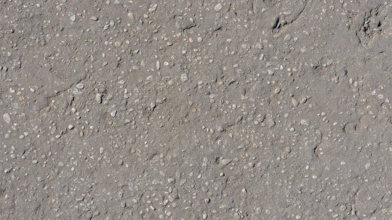 Photographie en gros plan de la surface d'une chaussée en asphalte montrant un désenrobage avec des particules de granulat détachées et une perte de matériau de surface sur une chaussée autoroutière