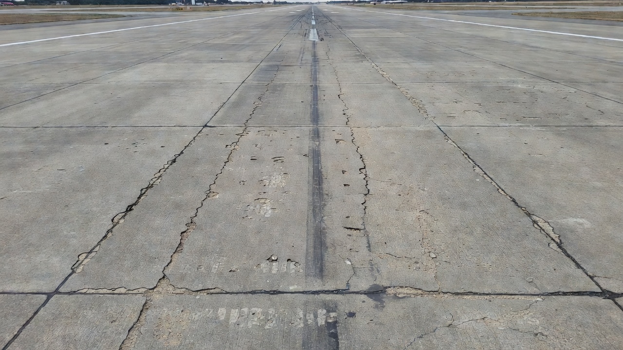 Vista aérea de pavimento de concreto de pista de aeropuerto que muestra deterioro de juntas y spalling
