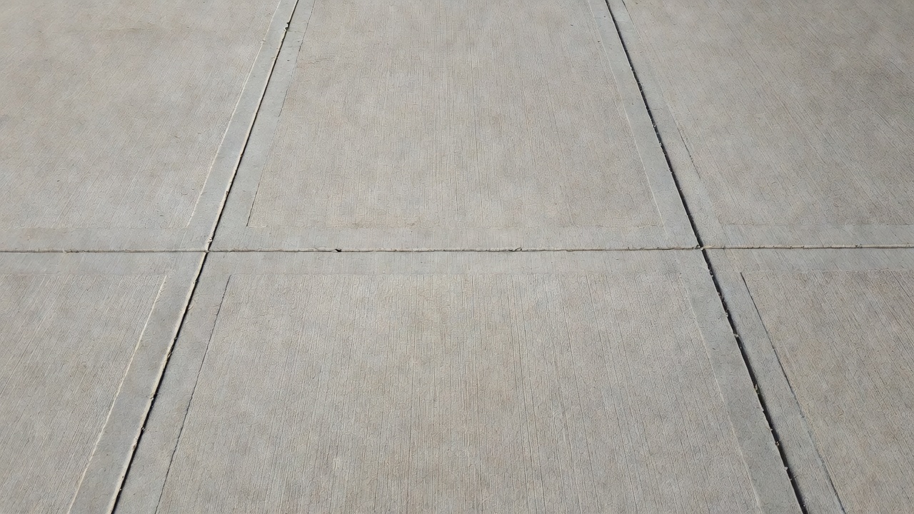 Jointed plain concrete pavement (JPCP) surface showing a transverse crack between two transverse contraction joints