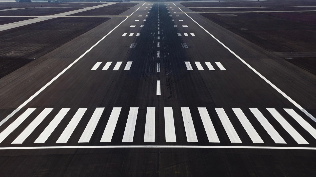 Precision instrument runway markings on an airport runway showing centerline stripes, threshold bars, and touchdown zone markers