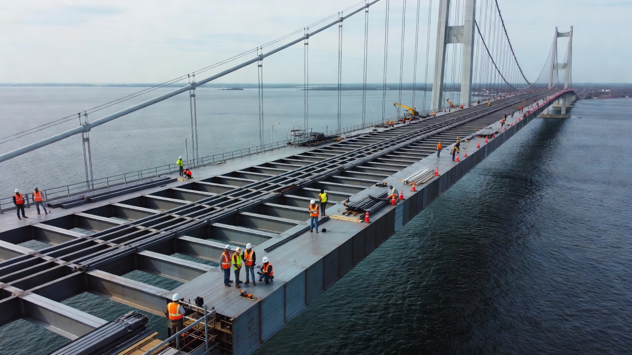 Luftaufnahme einer großen Hängebrücke mit orthotroper Stahlfahrbahn über Wasser, die das für weitgespannte Brücken typische aerodynamische Hohlkastendesign zeigt